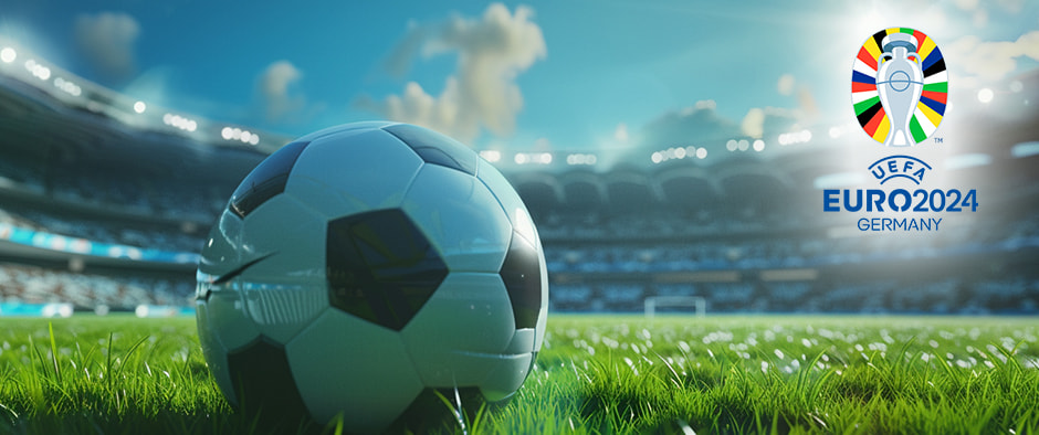 A close-up of a football on a lush green field in a stadium, with the bright UEFA Euro 2024 Germany logo prominently displayed in the background under a sunny sky.