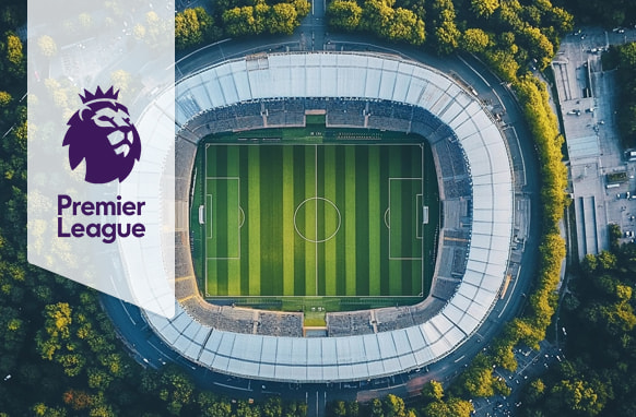  Aerial view of a football stadium surrounded by trees with the Premier League logo displayed on the left side.