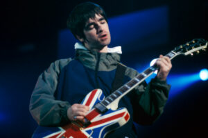 Noel Gallagher playing a guitar painted as a Union Jack.