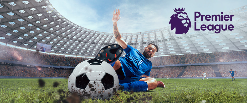 This image features a football player in a blue kit sliding across the pitch in an attempt to kick a football, with dirt and grass flying up from the ground, symbolising a high-energy, competitive moment. The scene takes place in a large stadium packed with fans, creating an atmosphere of excitement. The Premier League logo appears prominently in the top right corner, indicating that this action is part of the league's thrilling matches. The player's effort and determination are emphasised by his dramatic slide, reflecting the intensity of Premier League football.