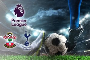 A close-up of two football players' feet as they compete for the ball on a grass pitch. The Premier League logo is displayed, along with the Southampton and Tottenham Hotspur club logos, in a brightly lit stadium.