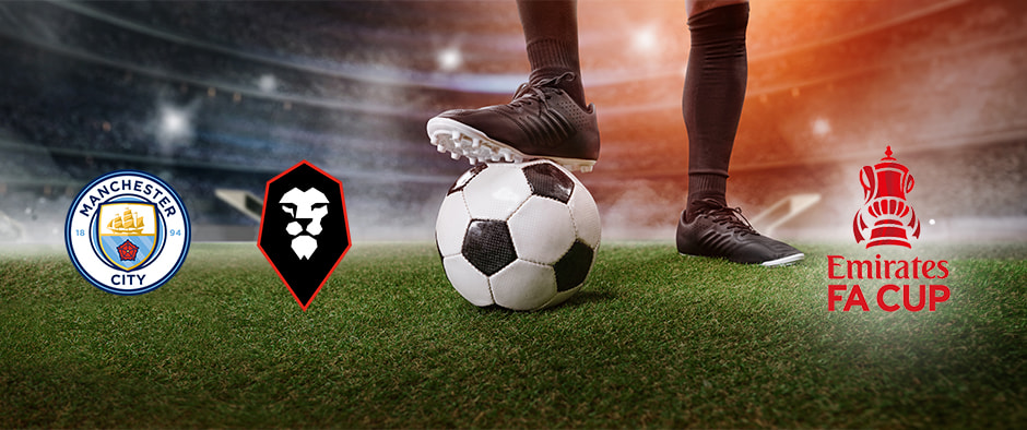 A football player stands ready to kick a ball on a lush green pitch under the bright stadium lights. The Manchester City and Salford City crests are prominently displayed alongside the Emirates FA Cup logo, highlighting their upcoming FA Cup match.